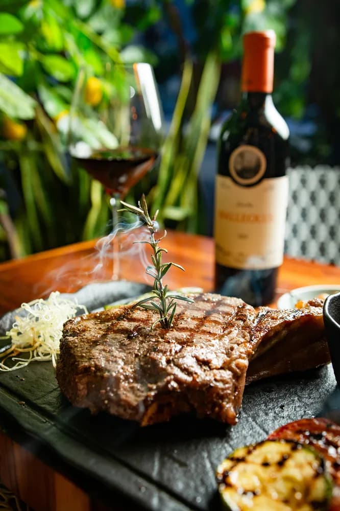 Corte premium a la parrilla con vino tinto servido en Rosatto Acapulco.
