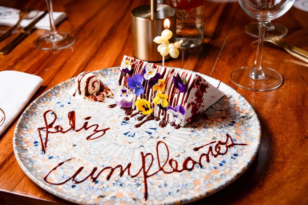 Postre de cumpleaños decorado con flores comestibles. Celebración personalizada en Rosatto Acapulco.